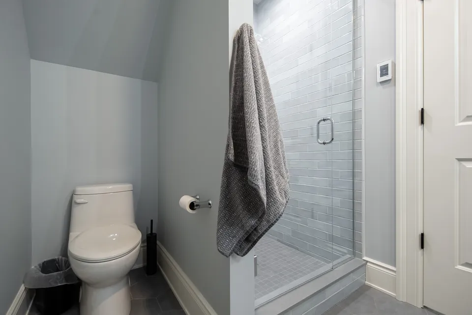 Gray subway tile shower with a glass door beside the toilet