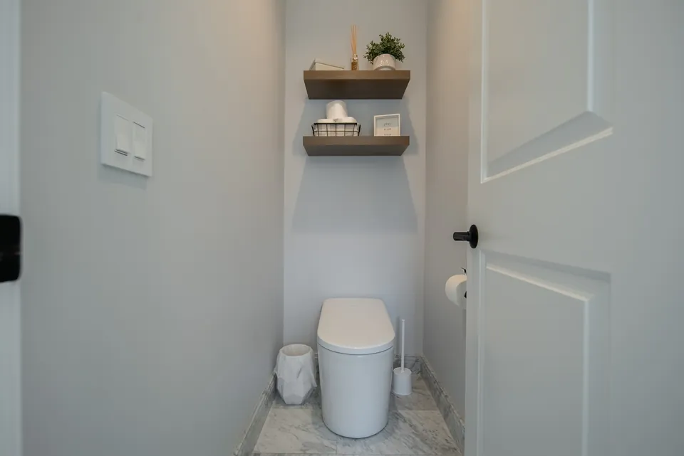 Separate toilet room with a smart toilet and floating wood shelves