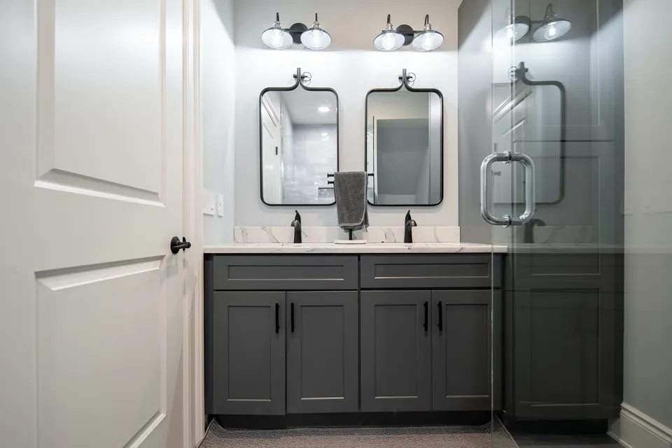 Charcoal shaker double vanity with a white top, black faucets and matching black-framed mirrors