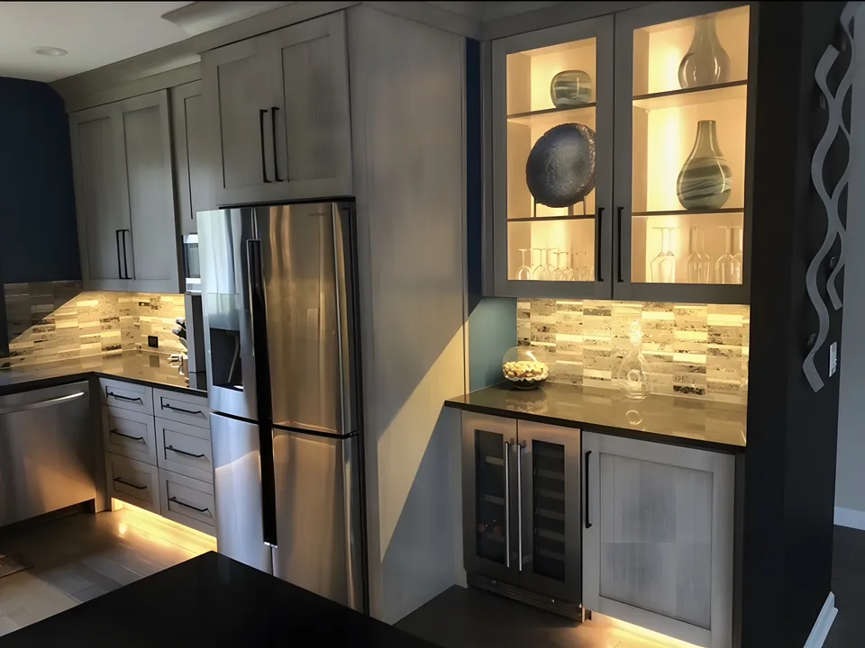 Lit glass-front upper cabinets and a beverage refrigerator in a dark gray kitchen