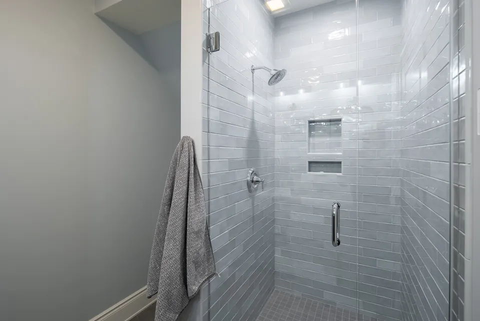 Walk-in shower with gray subway tile walls, a recessed niche and a frameless glass door